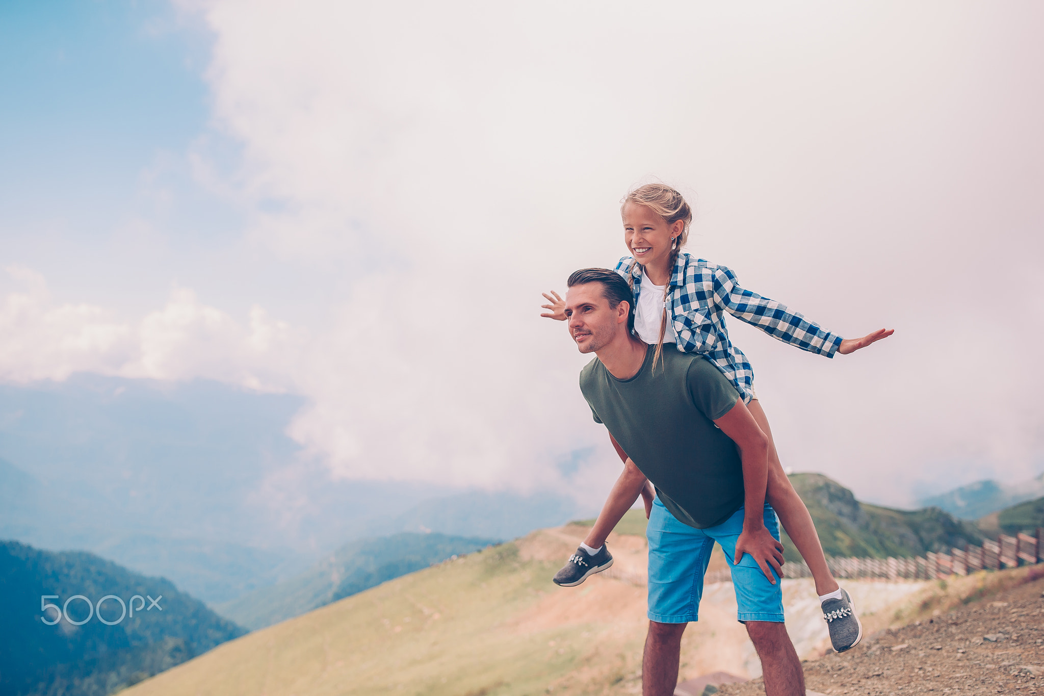 Beautiful little girl and young father in mountains in the background of fog