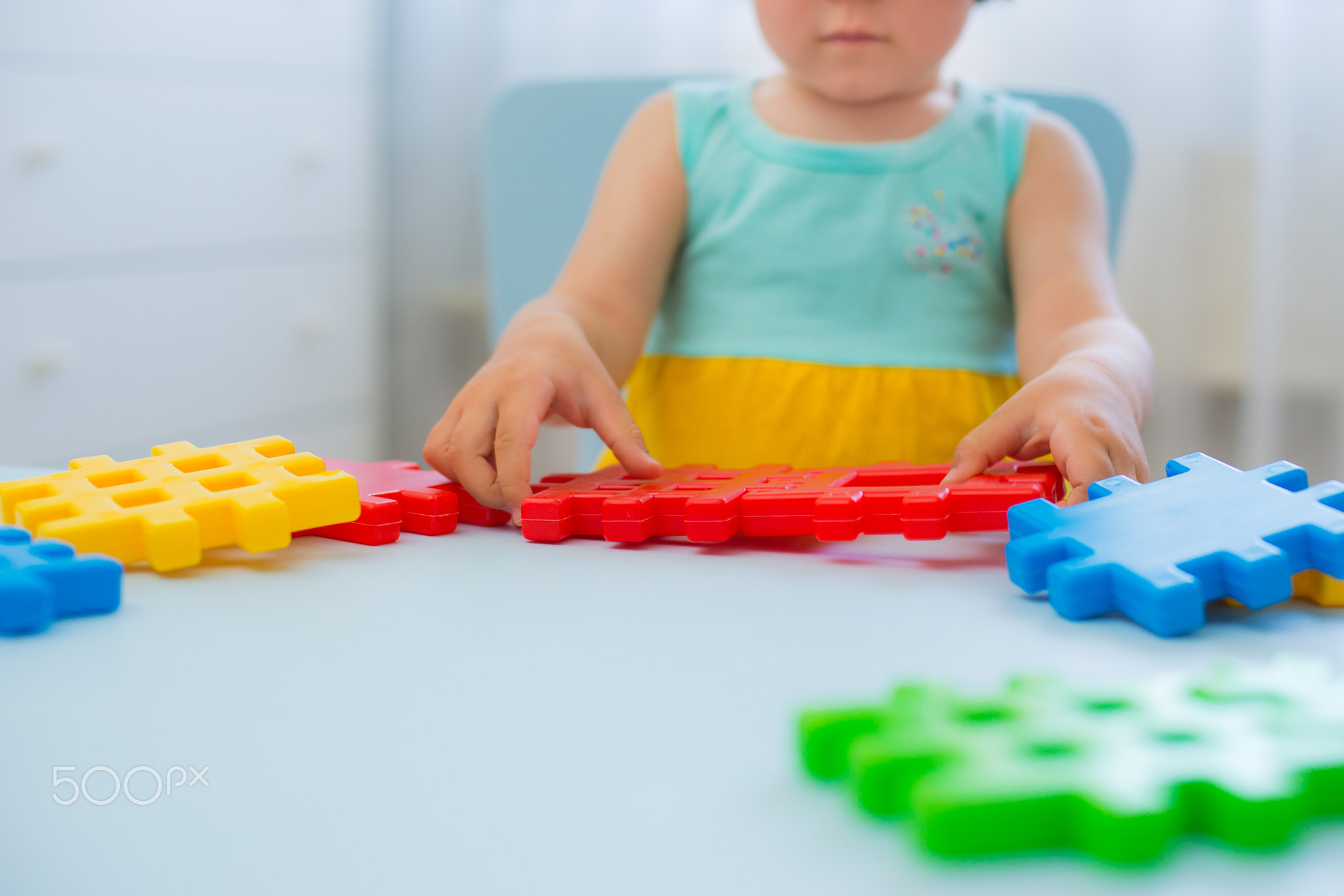 Preschool child 3 years playing with colorful toy blocks.