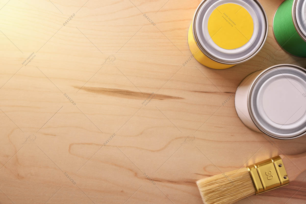 Paint pots and brush on wooden table with light effect