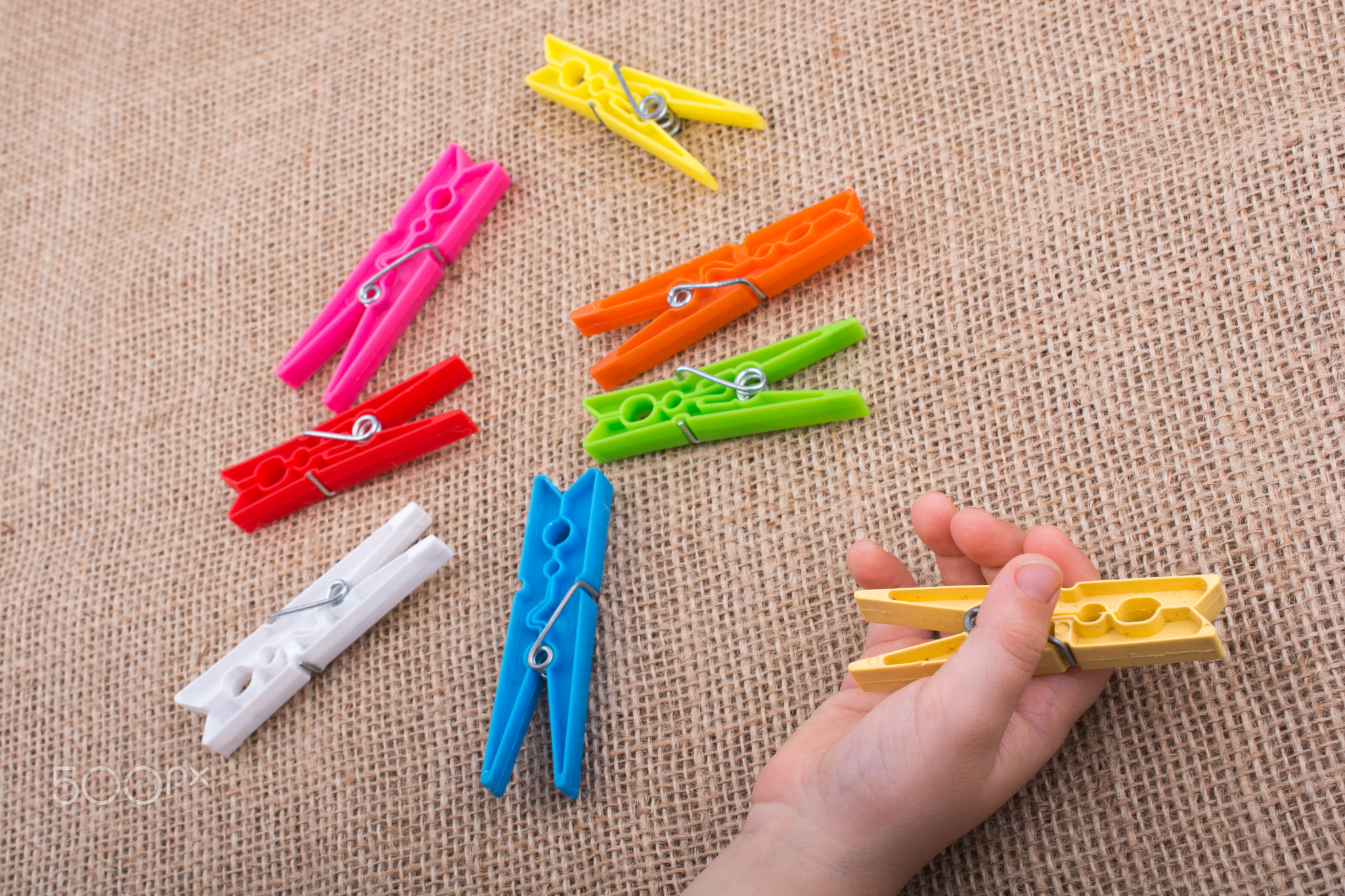 Clothespin in hand on a linen canvas background