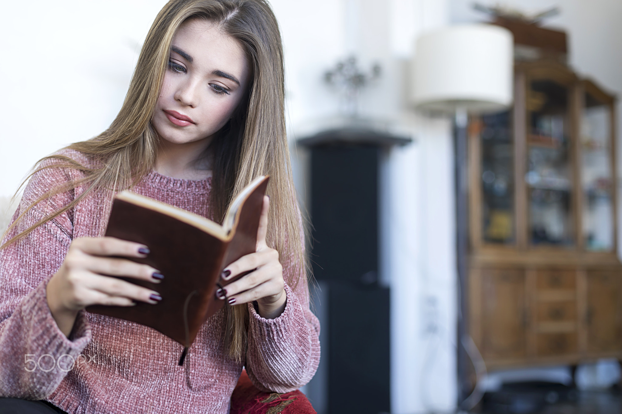 Relaxed woman reading a book on a sofa at home.