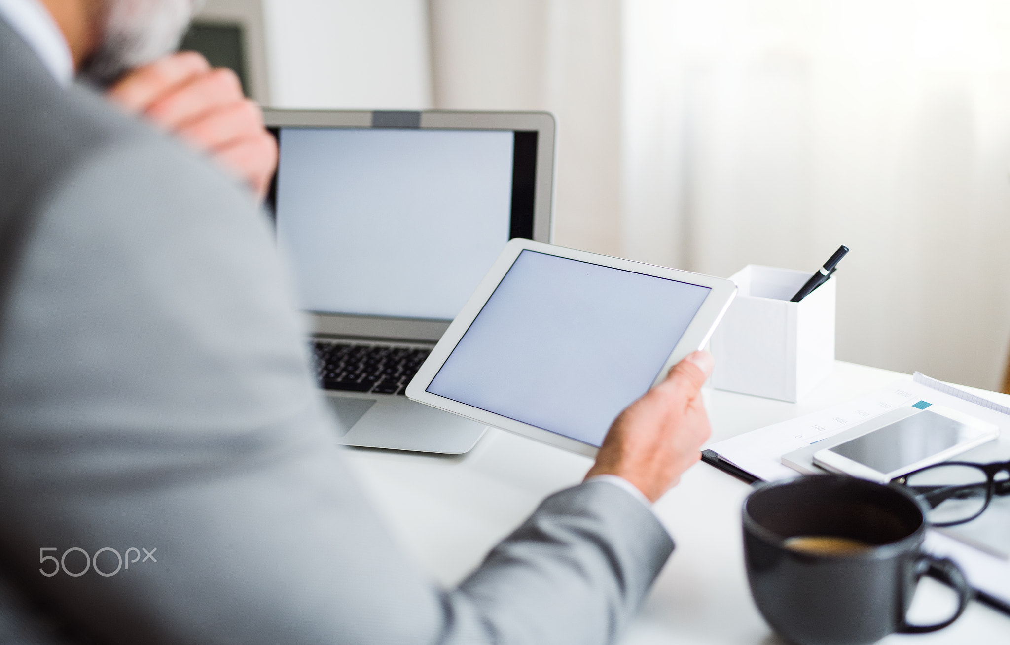 A midsection of businessman sitting at the table, using tablet. Copy space.