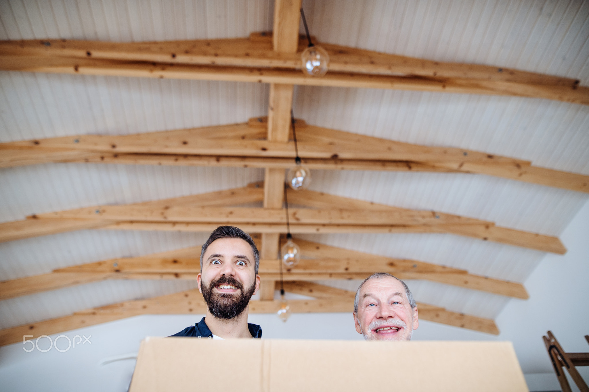 A mature man with his senior father furnishing new house, a new home concept.