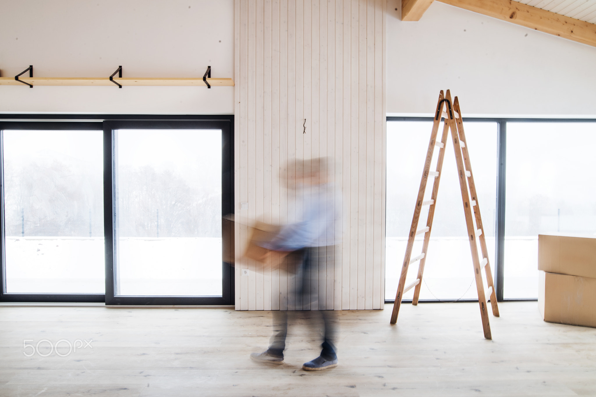 A man walking with cardboard boxes when furnishing new house. Motion blur.