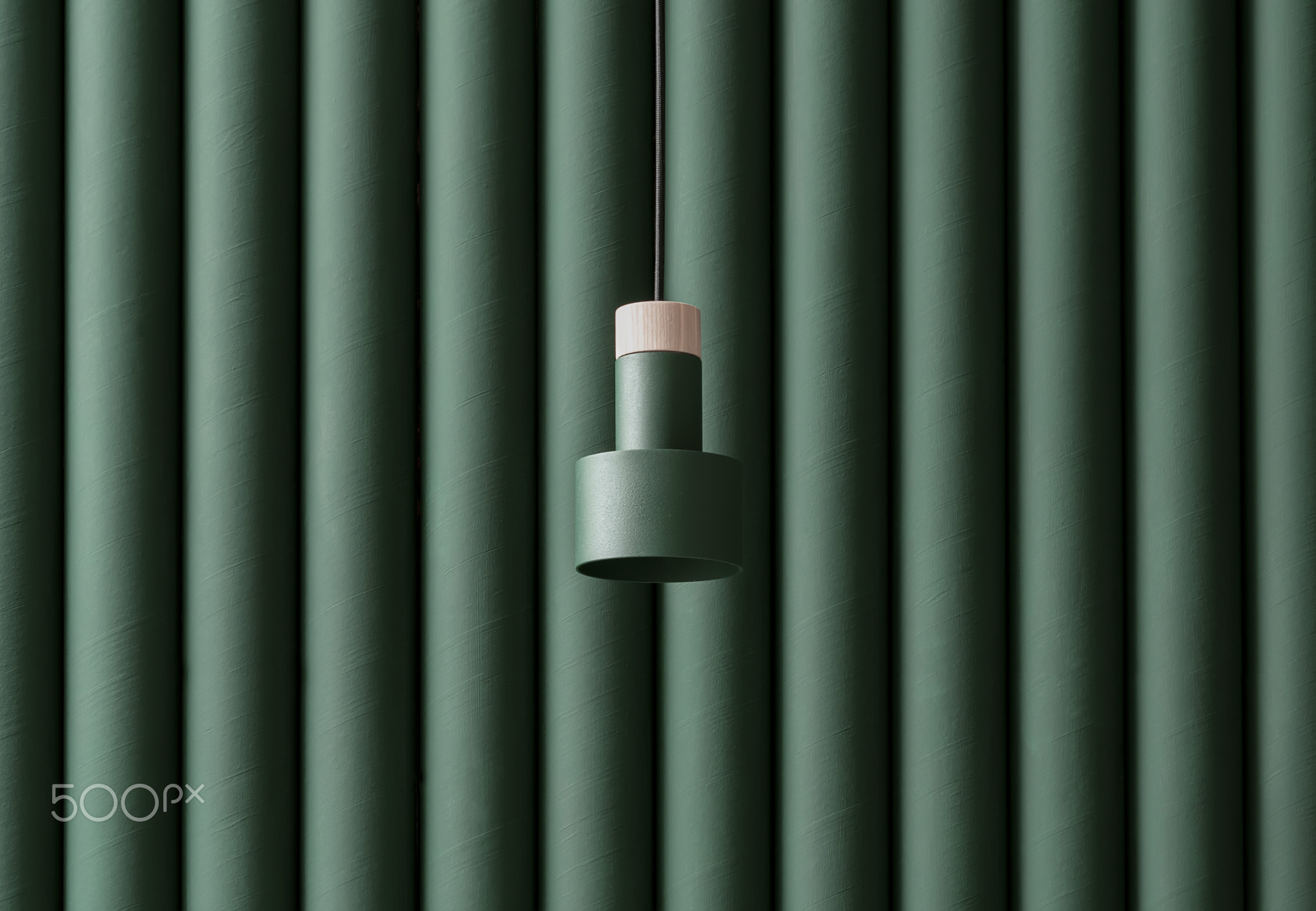 Dark green metal-wooden lamp hanging on folded colorful wall background in studio