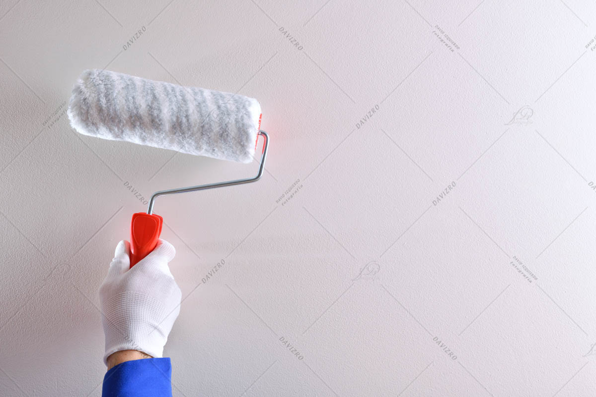 Hand of professional painter with roller on white wall