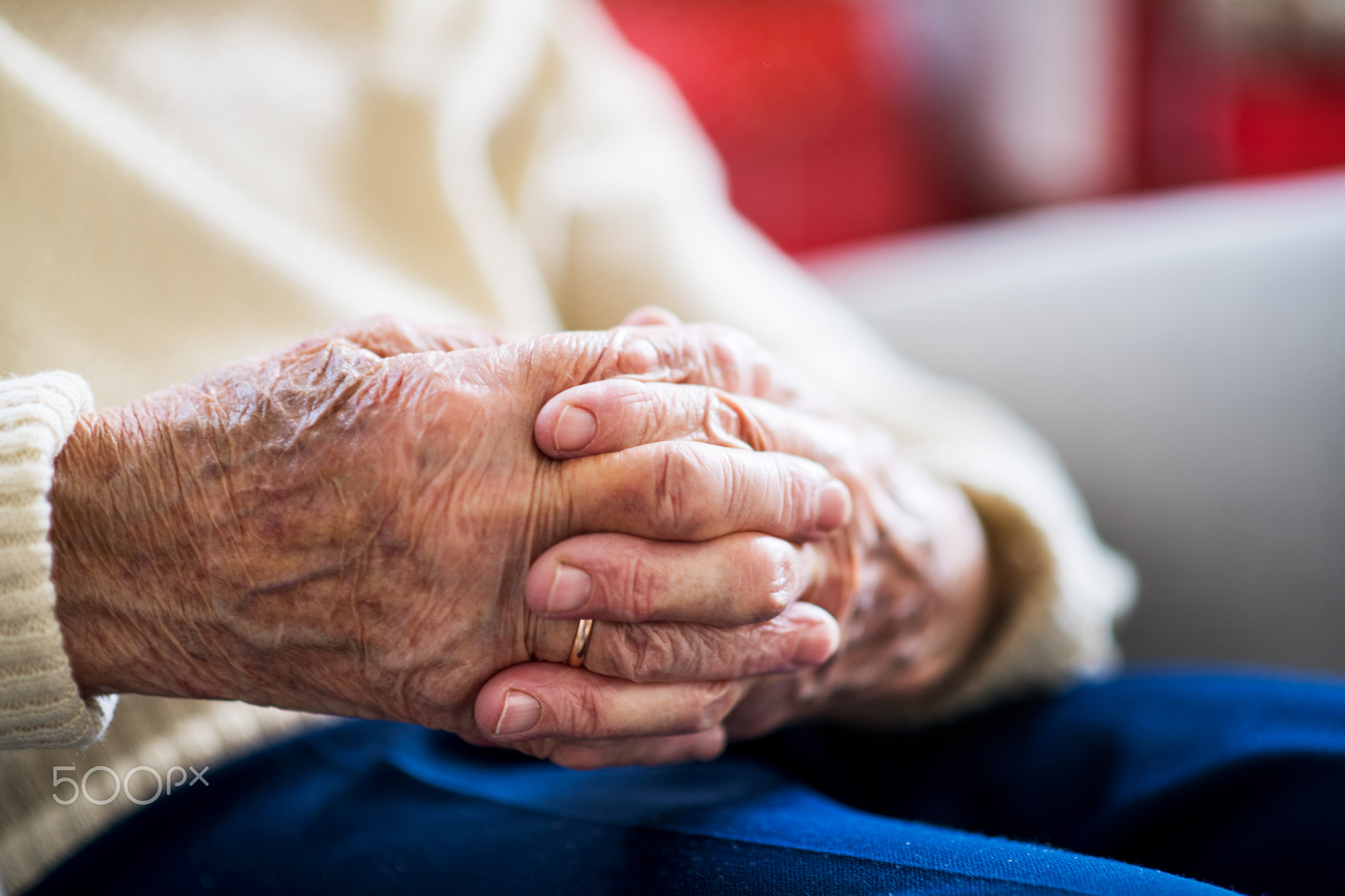 Close-up of a senior woman sitting and praying at home, hands clasped.