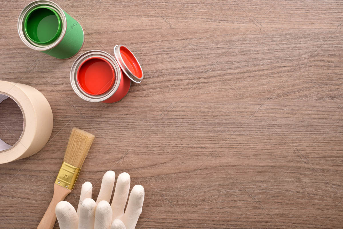 Two paint cans gloves and tape on wood top view