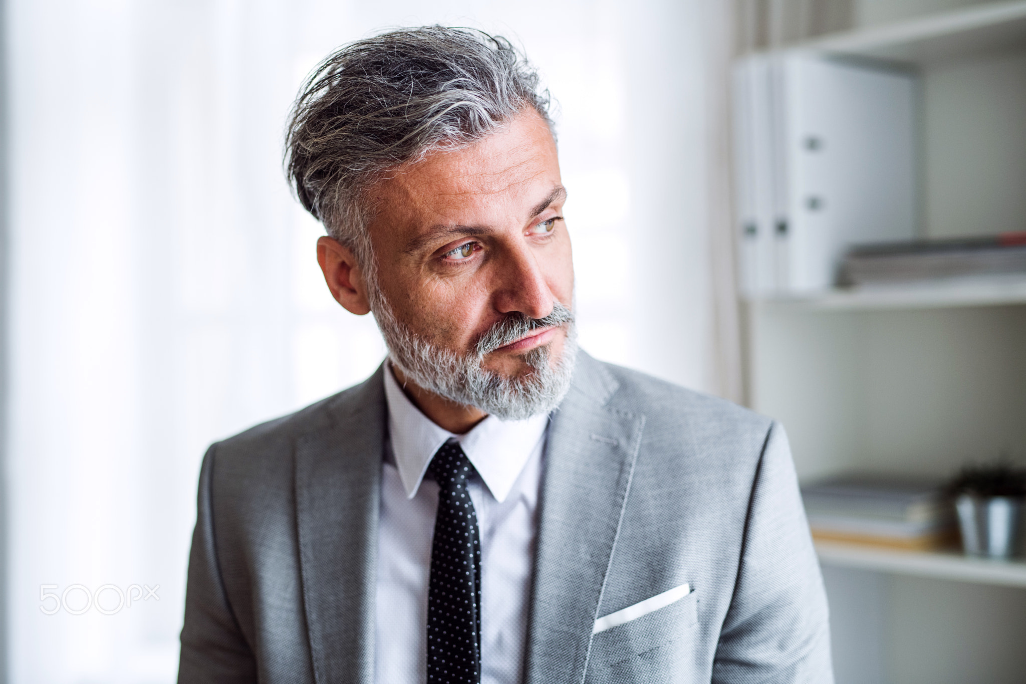 A serious mature businessman standing in an office.