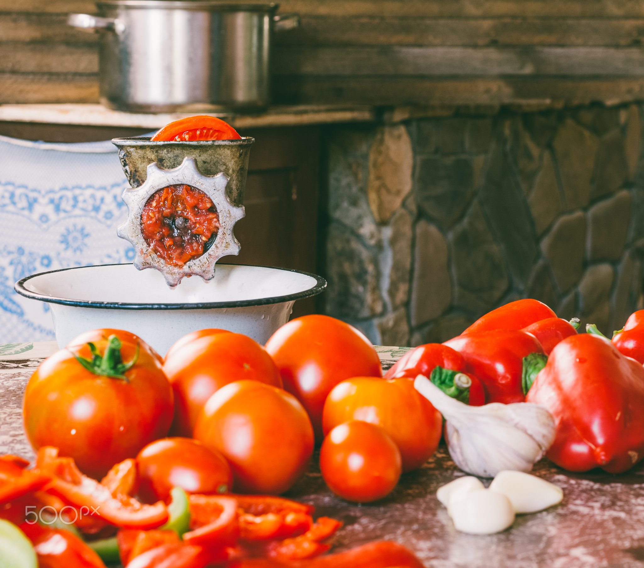 old vintage manual grinder and slices of fresh tomatoes, red bell pepper and garlic on the table...