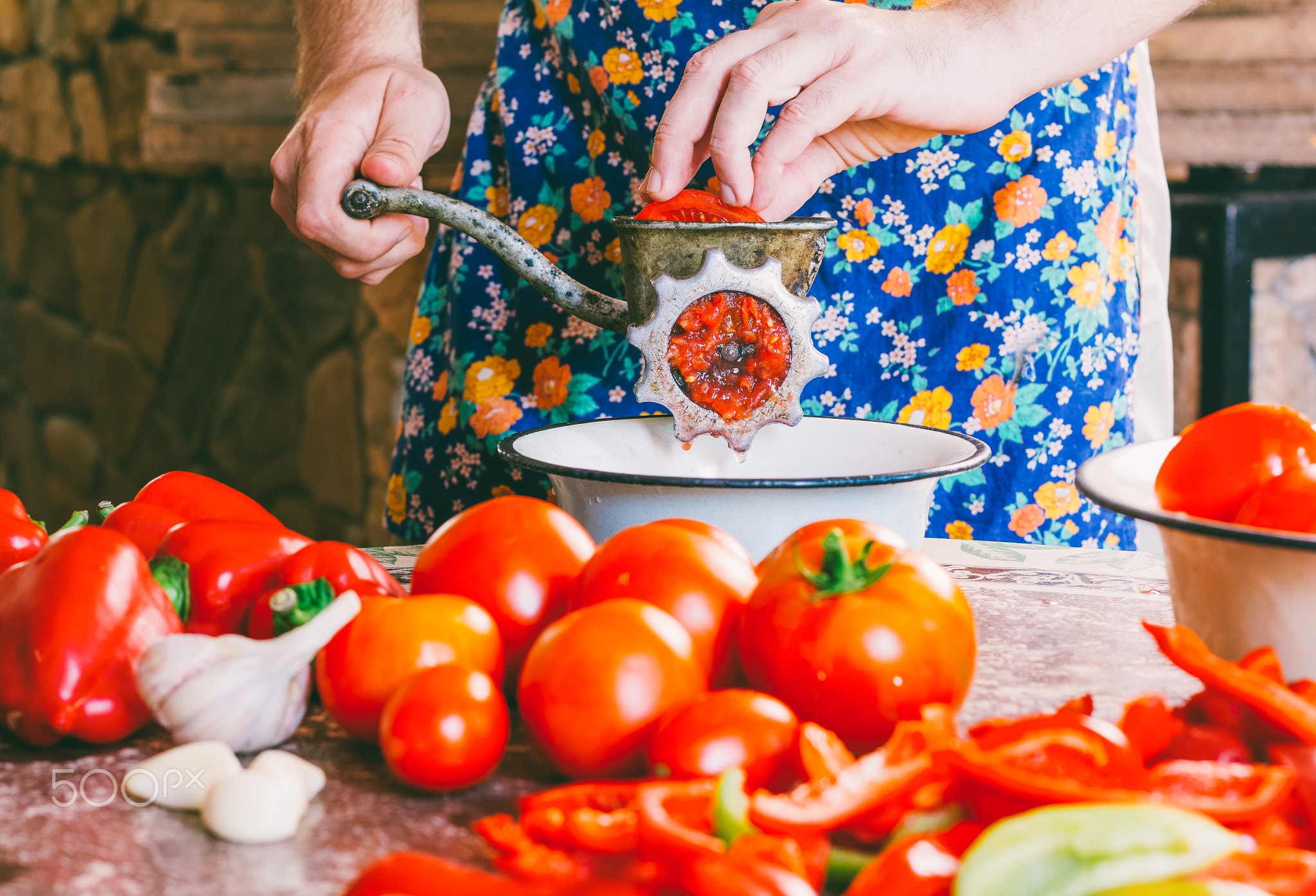the man cooks homemade sauce, ketchup grinds pieces of ripe tomatoes into an old vintage hand...
