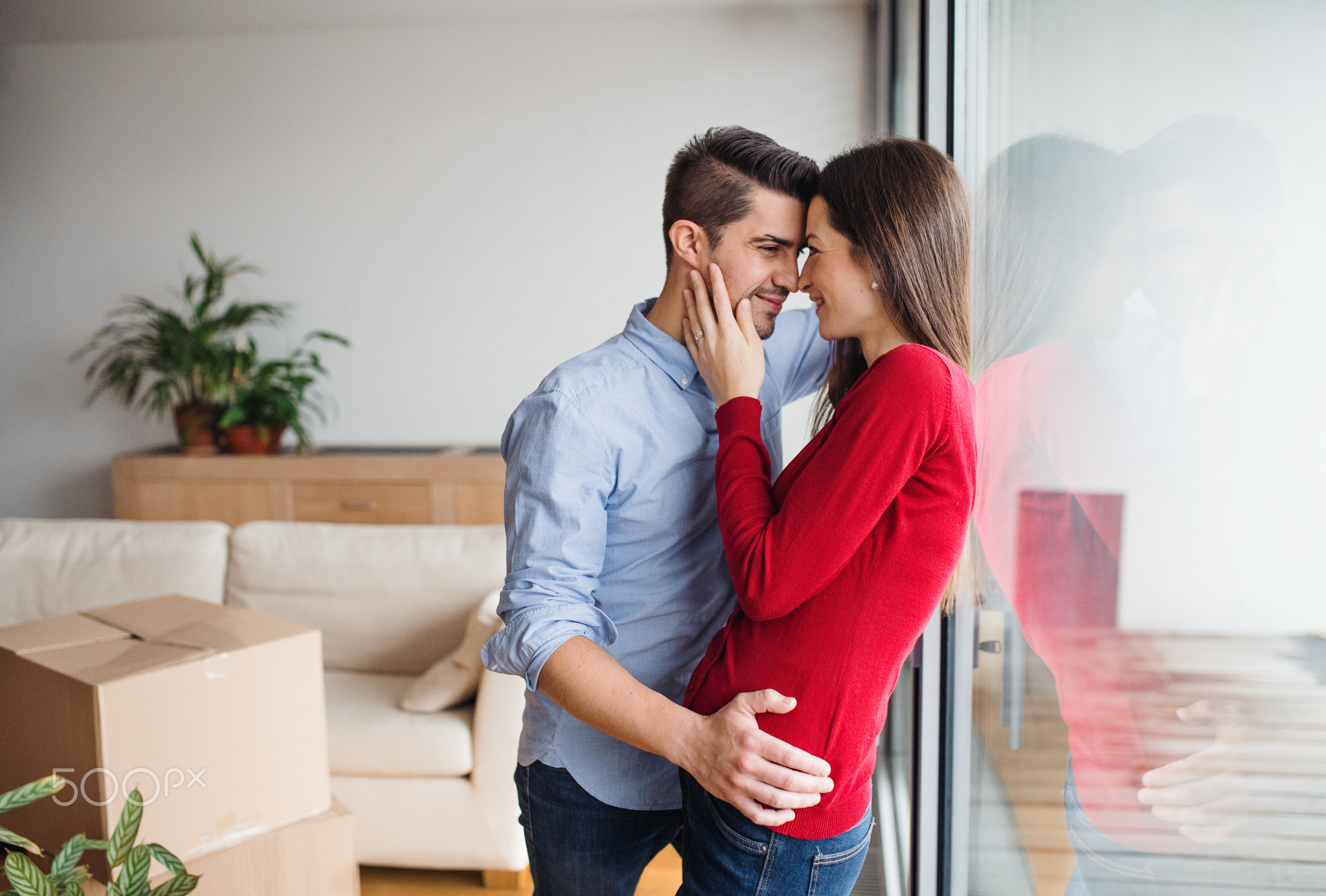 Young couple moving in a new home, hugging.