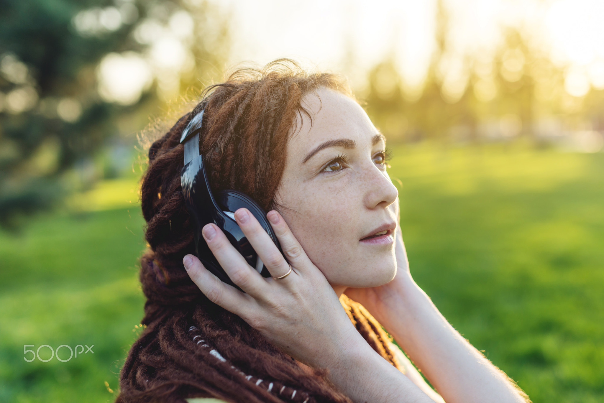 Beautiful modern girl with dreadlocks listening to music with he