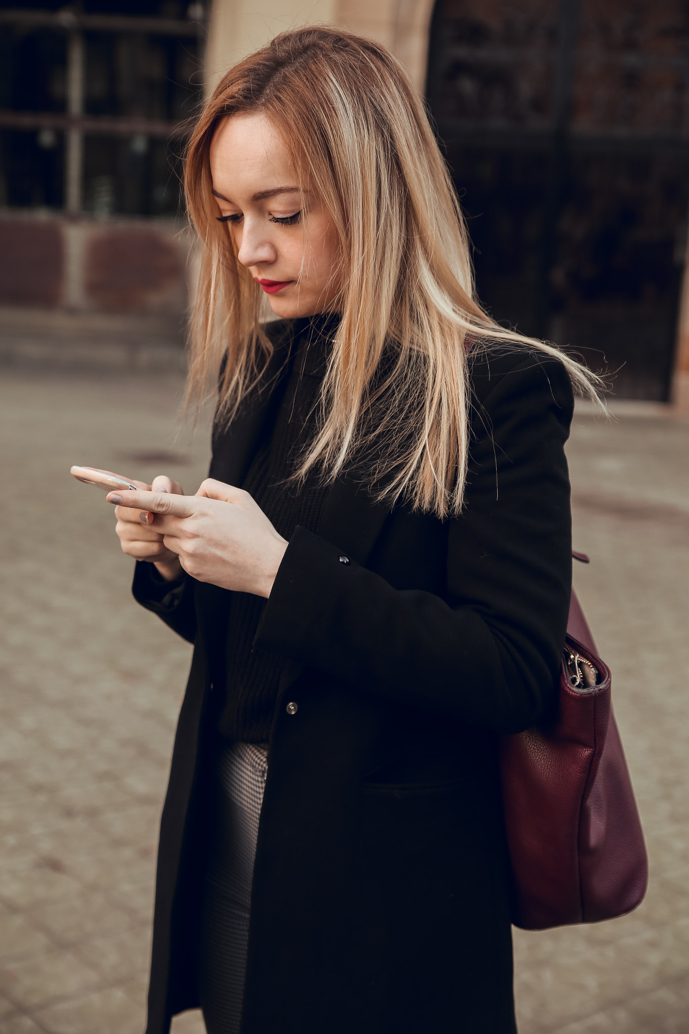 Blonde girl in the street using mobile phone at sunset in Barcelona
