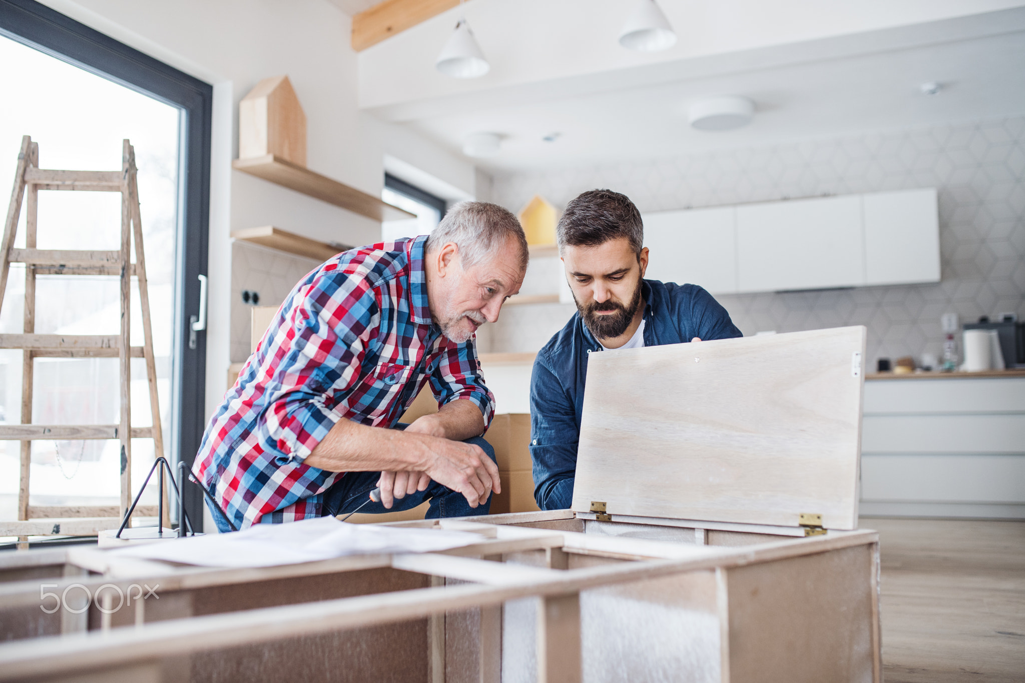 A mature man with his senior father assembling furniture, a new home concept.