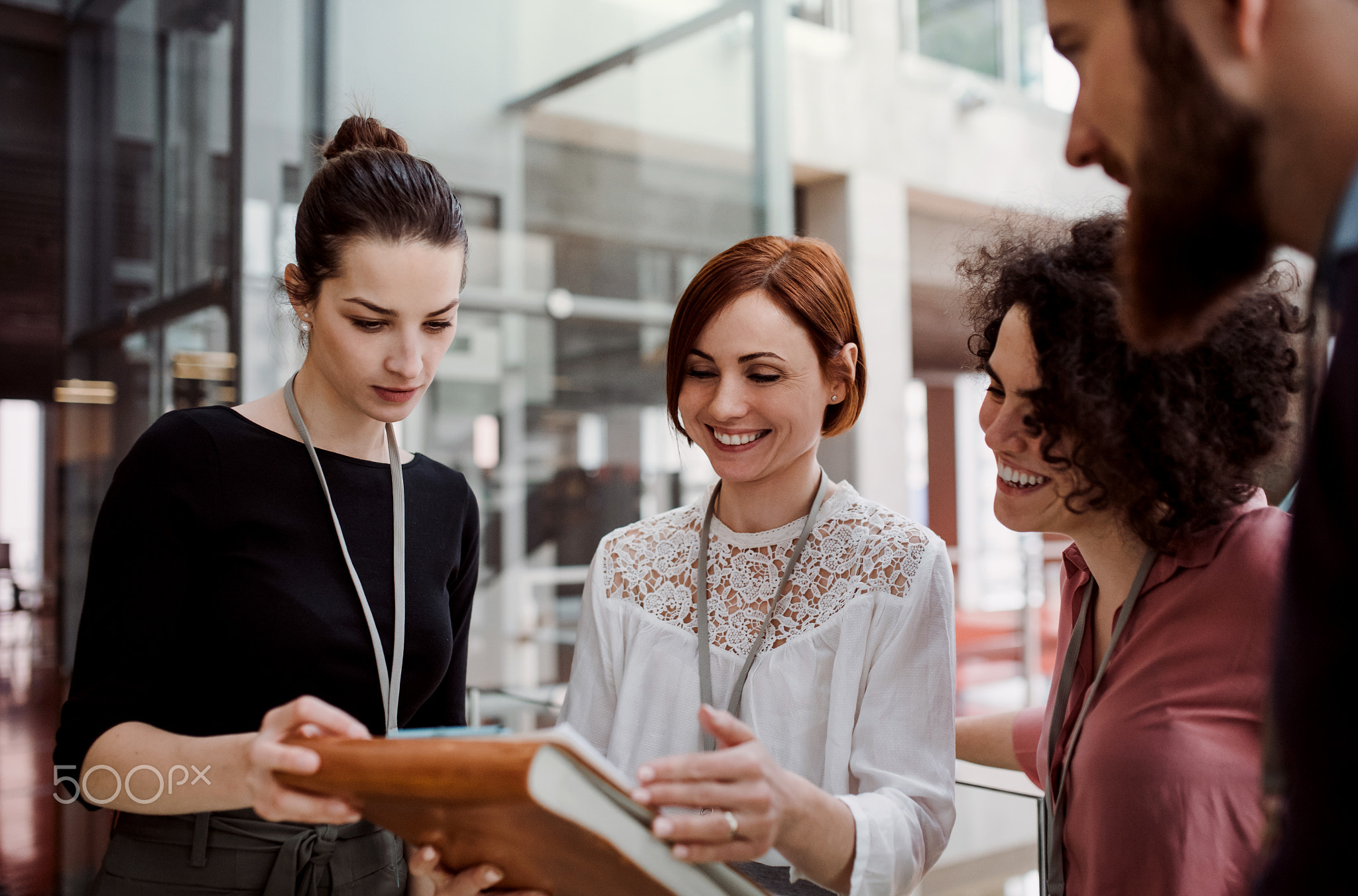 Group of young businesspeople standing together in office, talking.