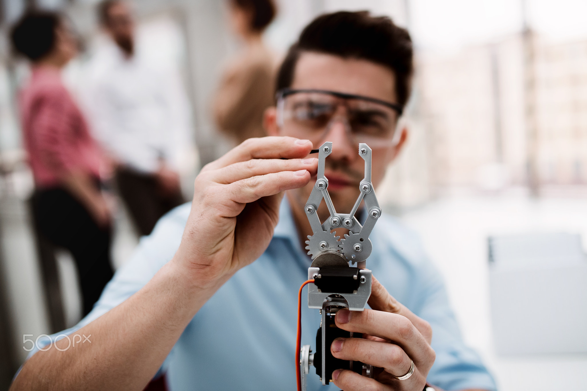 A young businessman or scientist with robotic hand standing in office, working.