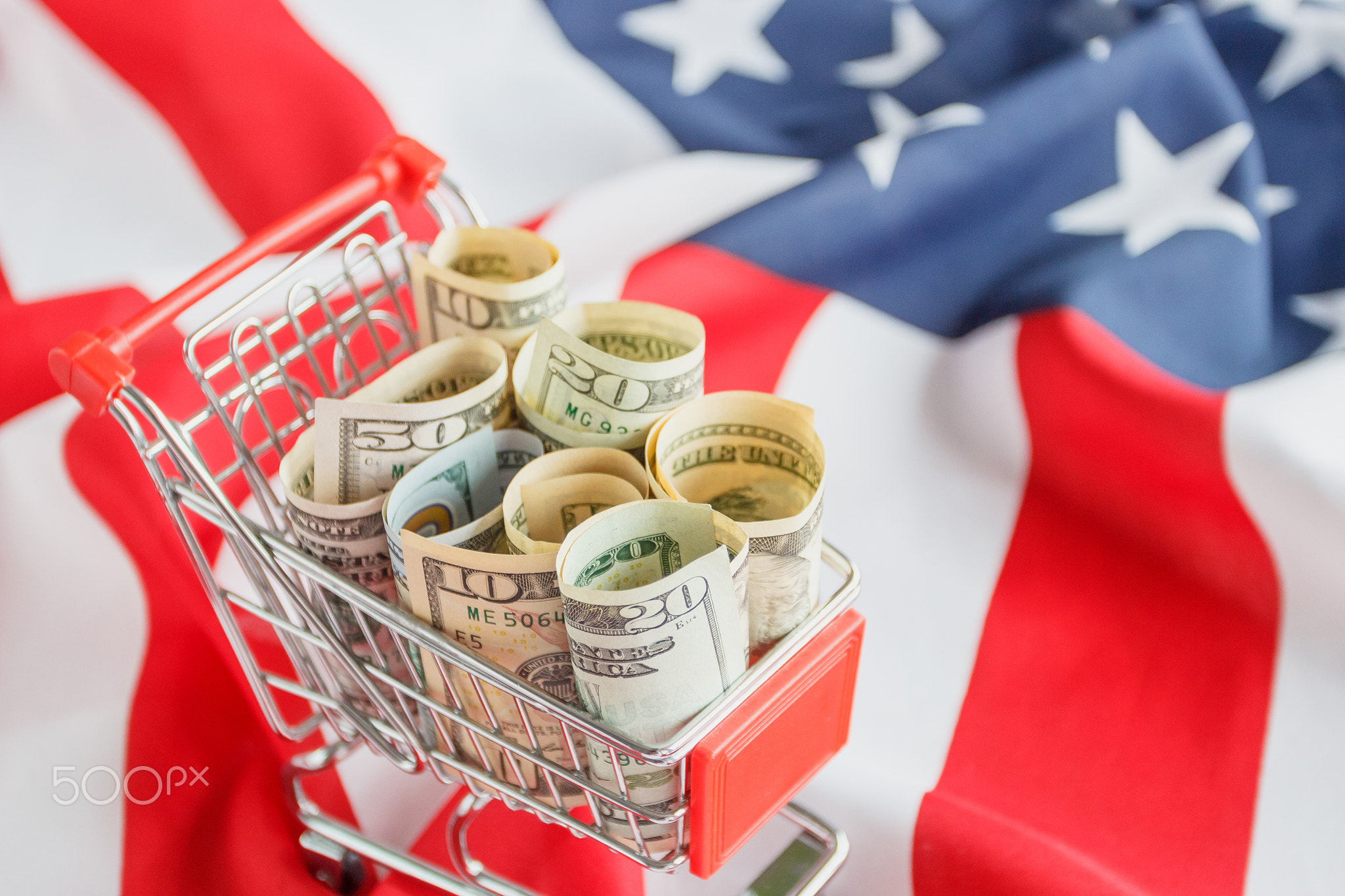 Shopping cart with American dollars inside on the national flag of United States of America