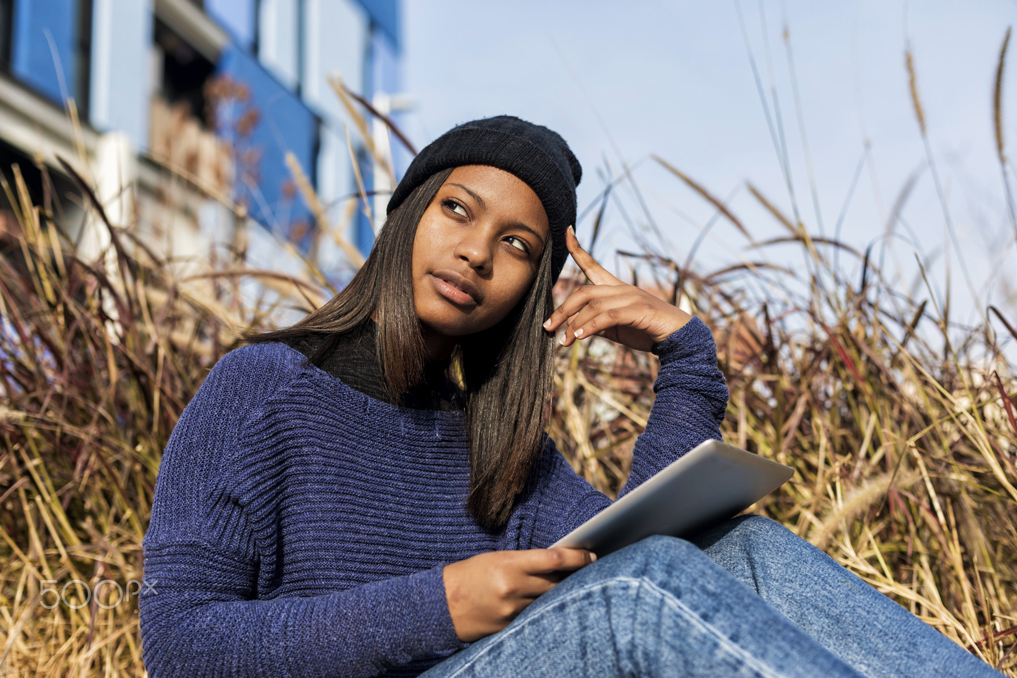 Portrait of a beautiful young smiling african woman using tablet pc computer sitting in the city...