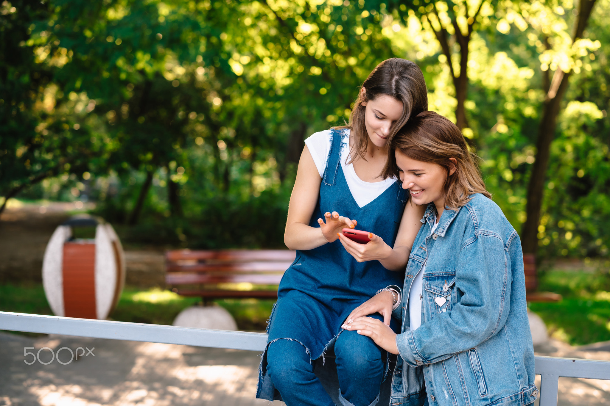 Two female girlfriends look at the smartphone at the pack