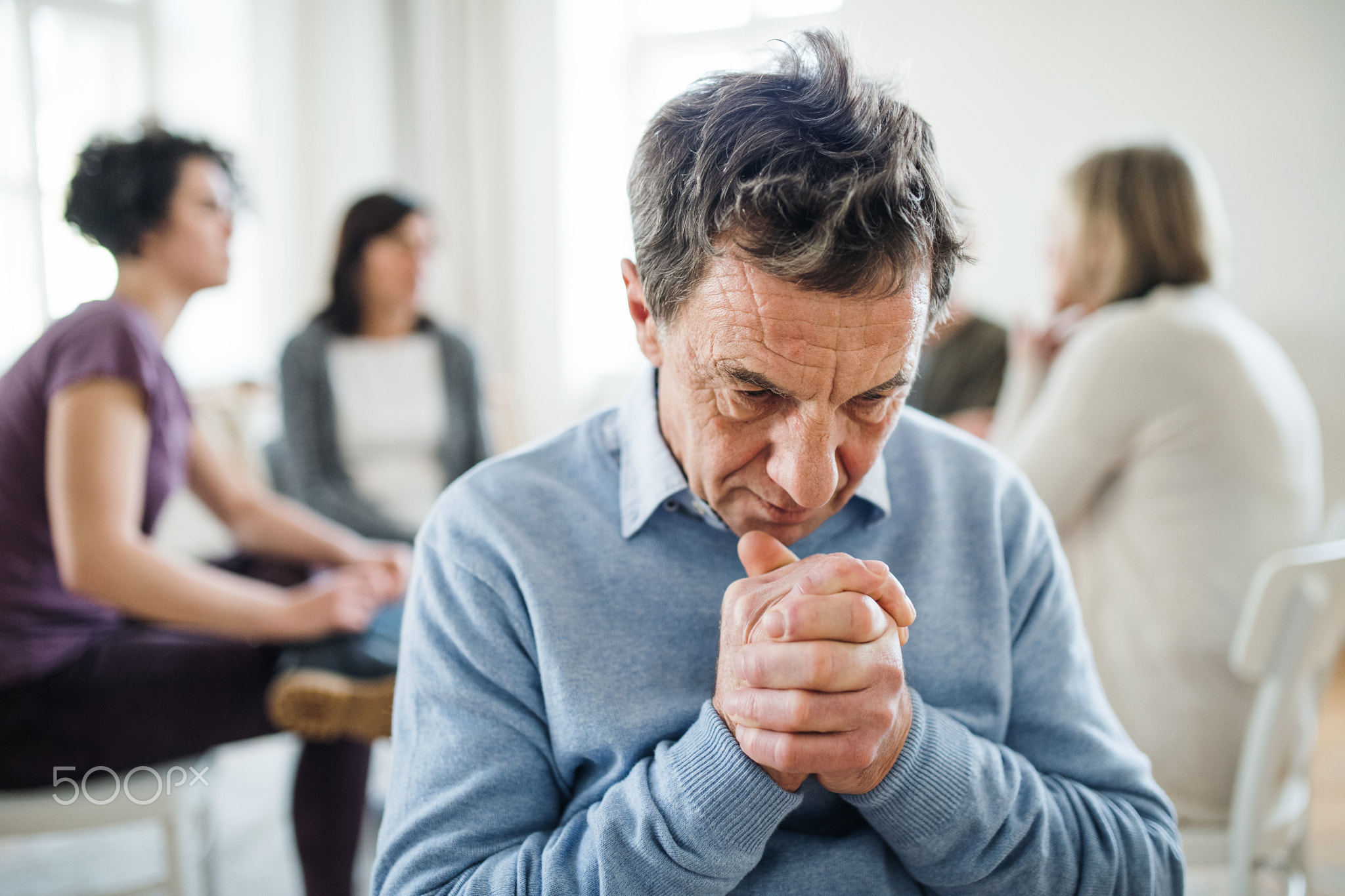 A portrait of senior depressed man during group therapy.