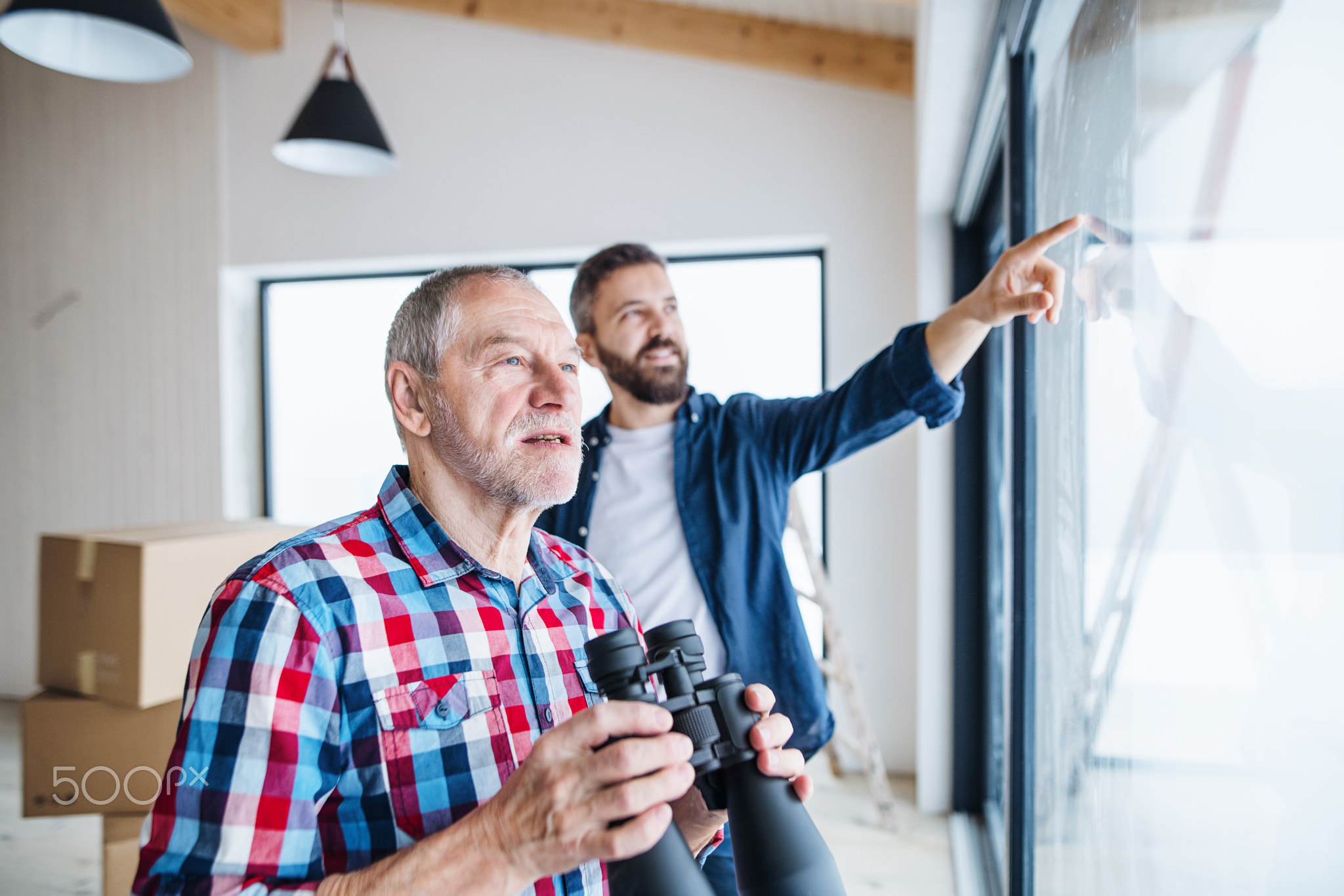 A senior man helping his son with furnishing new house, a new home concept.