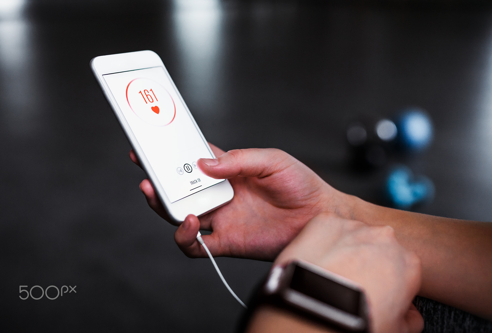 A midsection of woman with smartphone in a gym, checking heart rate.