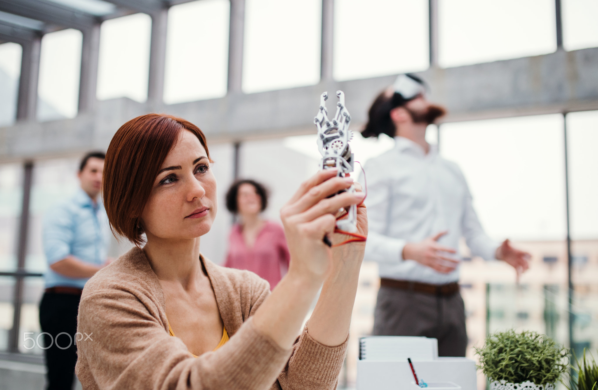 Young businesswoman or scientist with robotic hand standing in office, working.