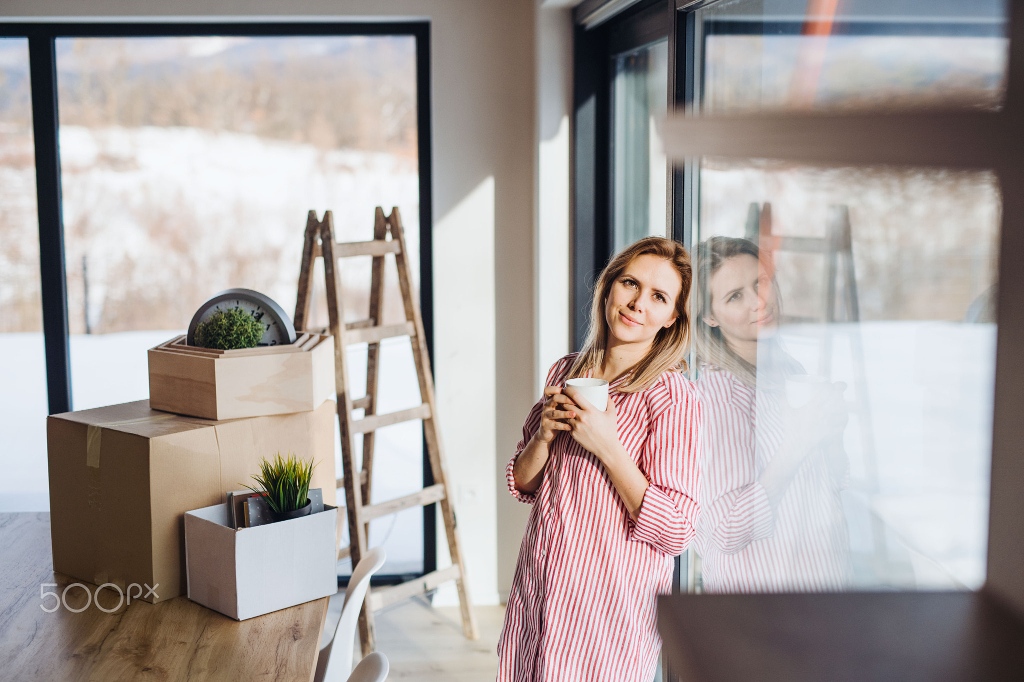 A young woman moving in new home, drinking coffee.