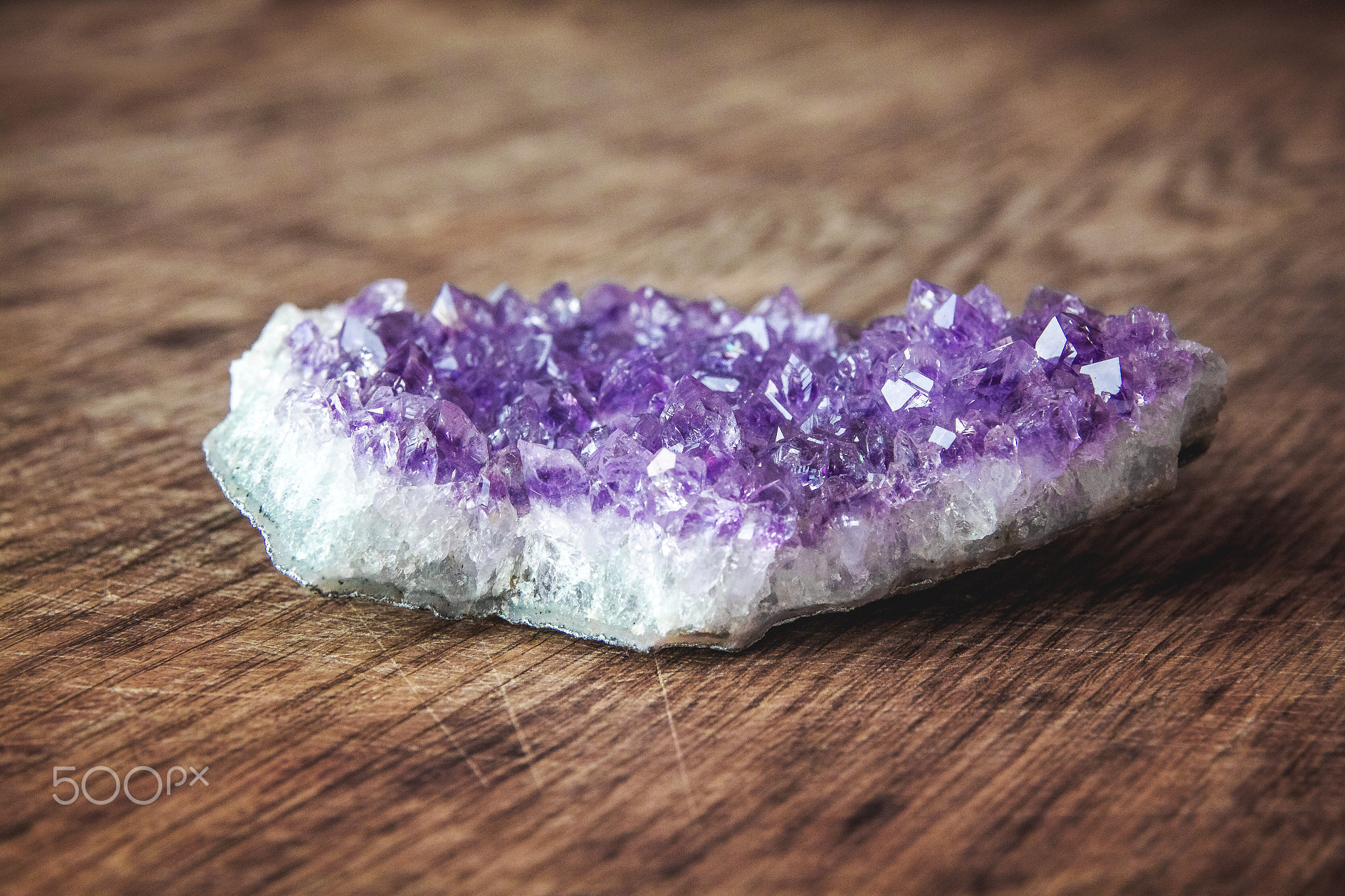 Close-up of amethyst stone druse crystals on dark granite polished slab. Texture of crystals of...