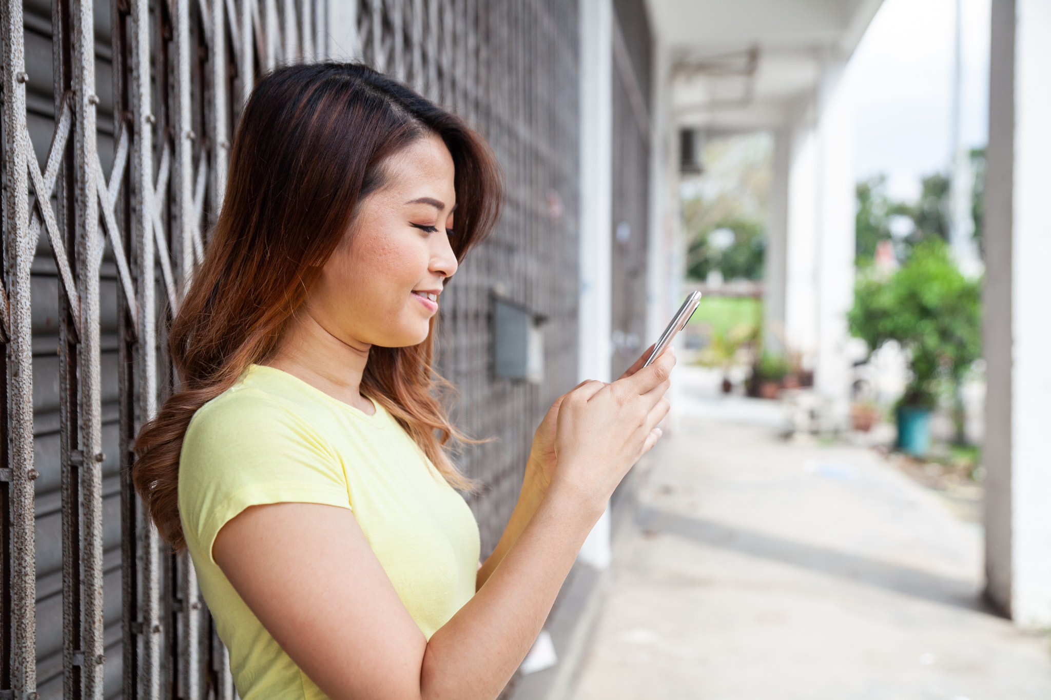 Asian girl using phone near shoplots.jpg