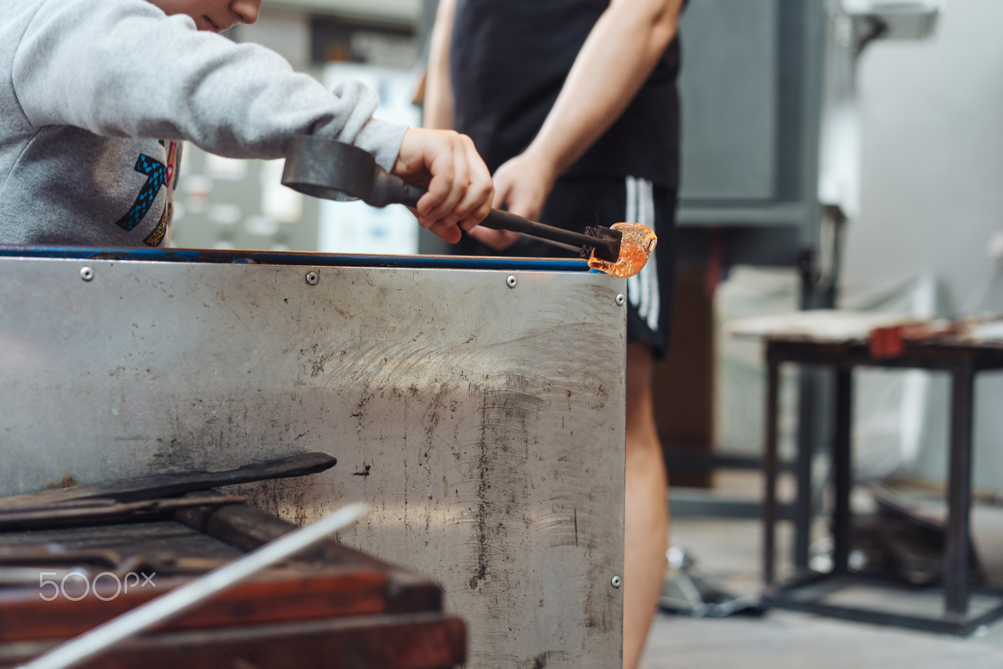 A glassblower student tries to make a flower out of glass