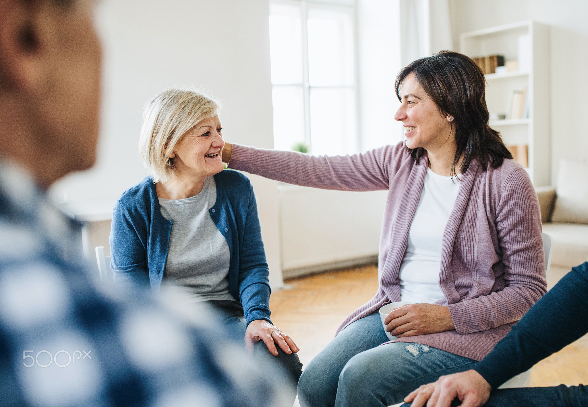 Men and women sitting in a circle during group therapy, supporting each other.