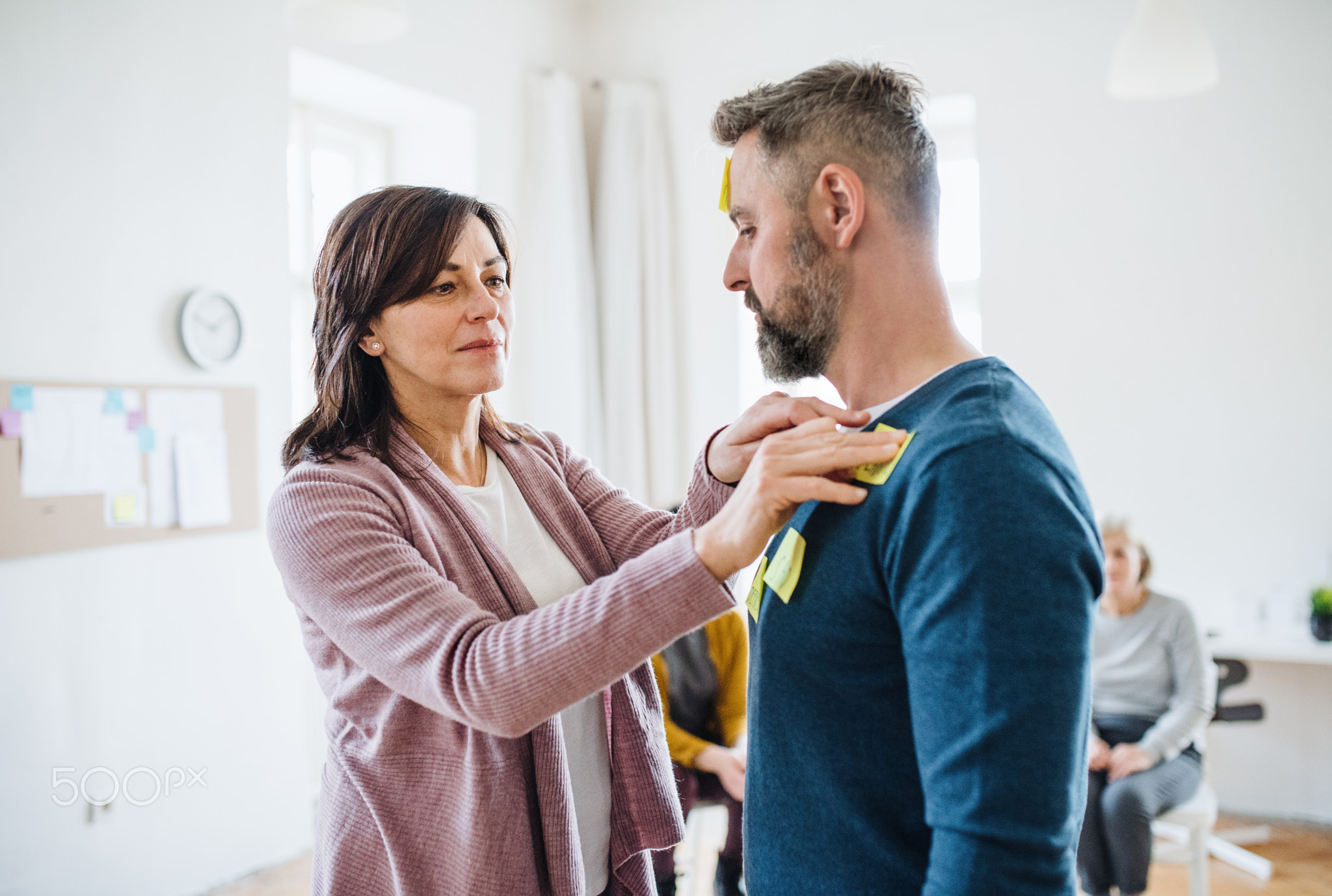 Counsellor putting an adhesive notes on client during group therapy.