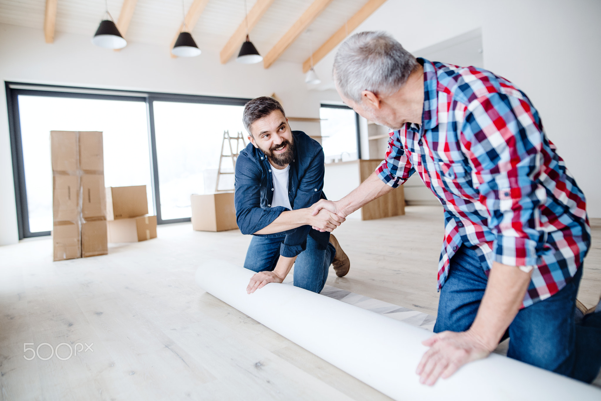 A senior man helping his son with furnishing new house, a new home concept.