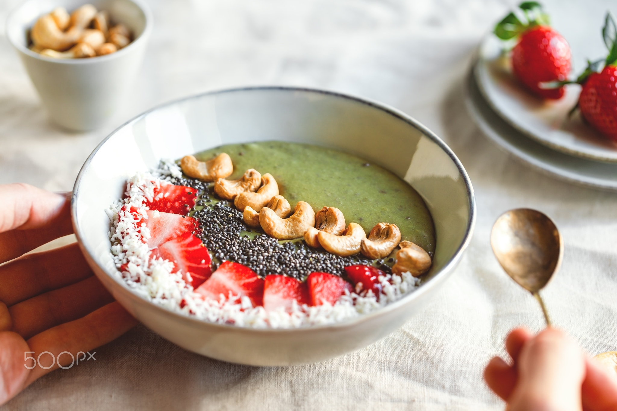 Green smoothie bowl with coconut cream, banana, strawberry, cashew and chia seeds. Healthy vegan...