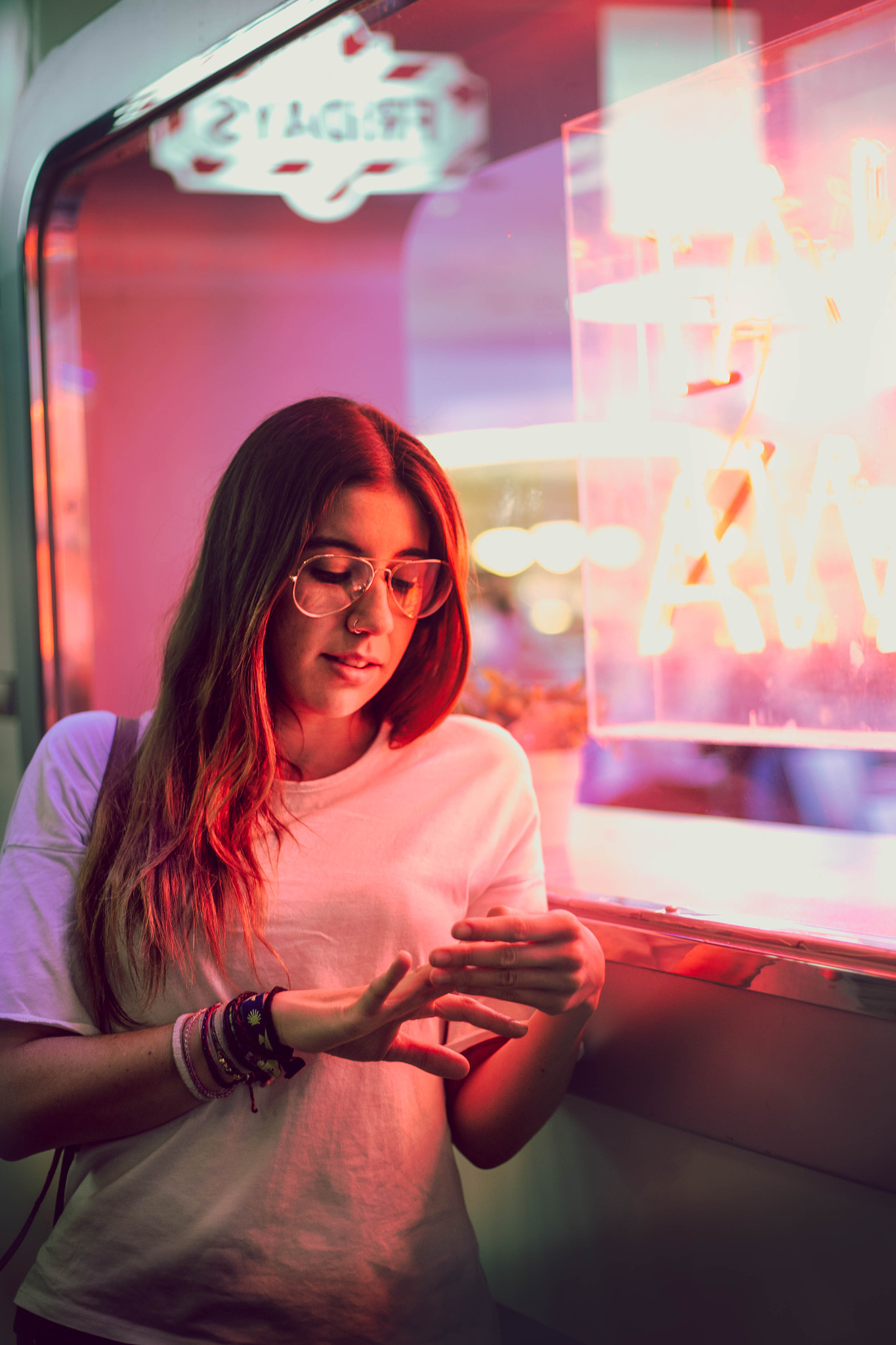 young woman looking at her nails with aviator glasses in the door next to a club with a window...