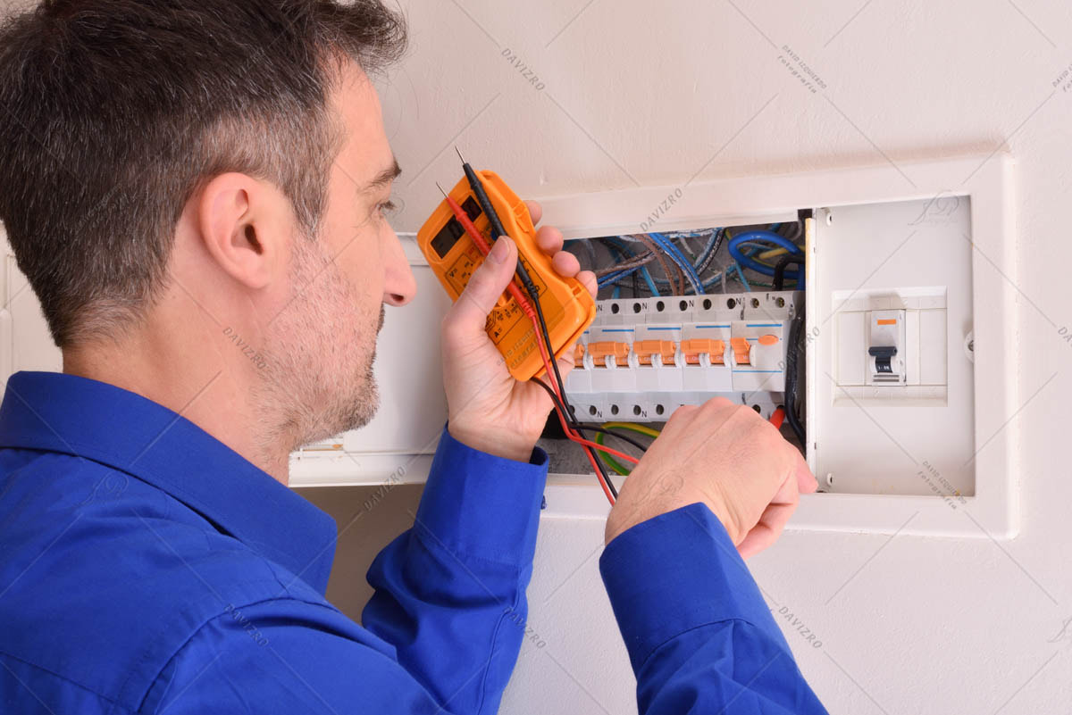 Electrician doing repairs in electrical housing box