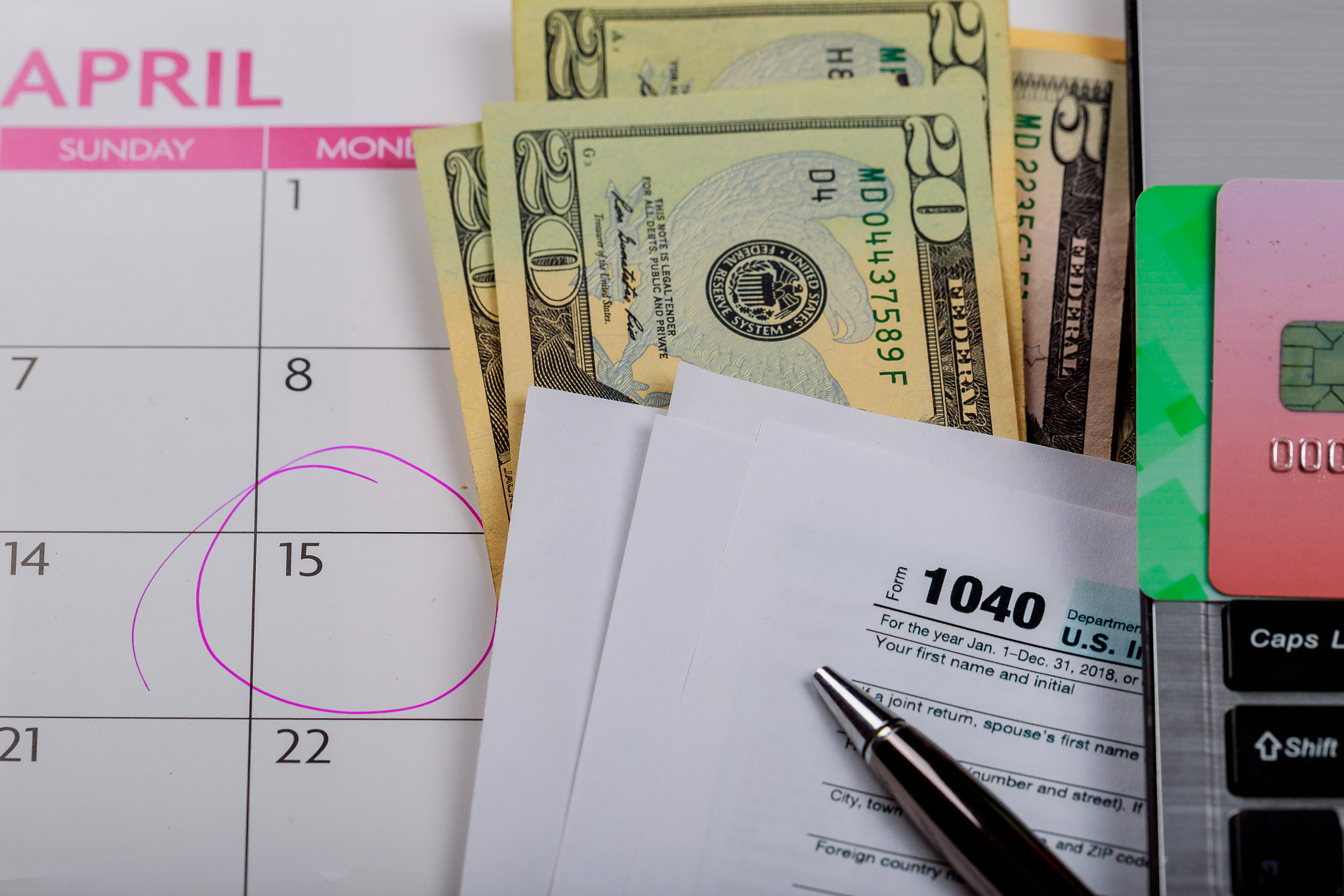 Tax time Closeup of U.S. 1040 tax return with U S dollars bills and for April Calendar