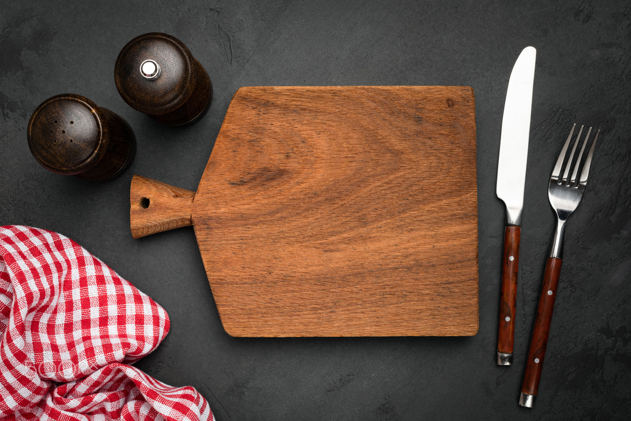 Cutting board, cutlery and plaid kitchen napkin