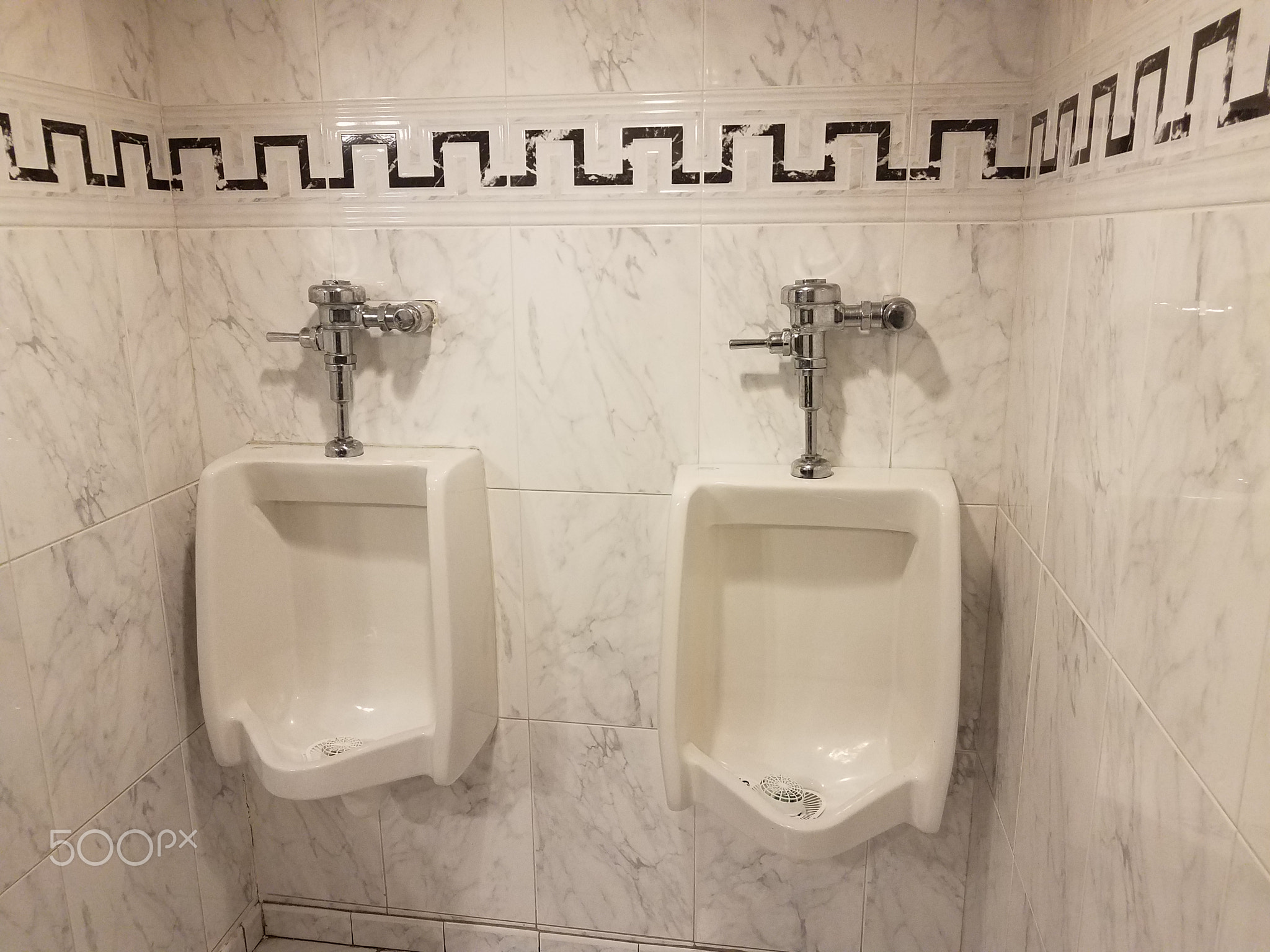 white and black tiles and urinals in restroom