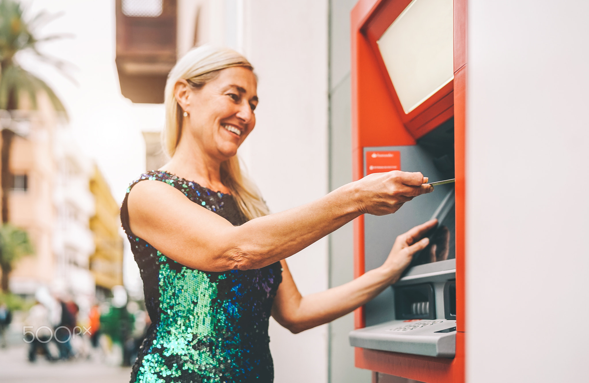 Happy mature woman withdraw money from bank cash machine