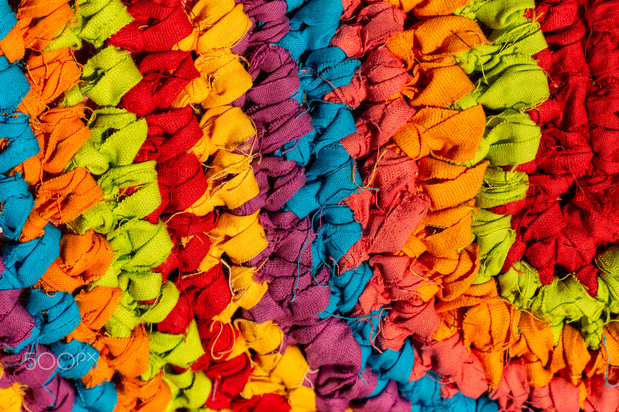 Rustic fabric with bright colors. Interlaced fabrics of colors forming a carpet. Recycling of...