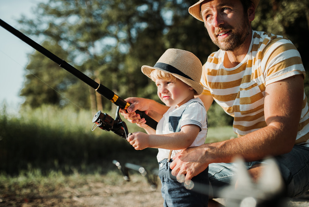 A mature father with a small toddler son outdoors fishing by a lake. by Jozef Polc on 500px.com