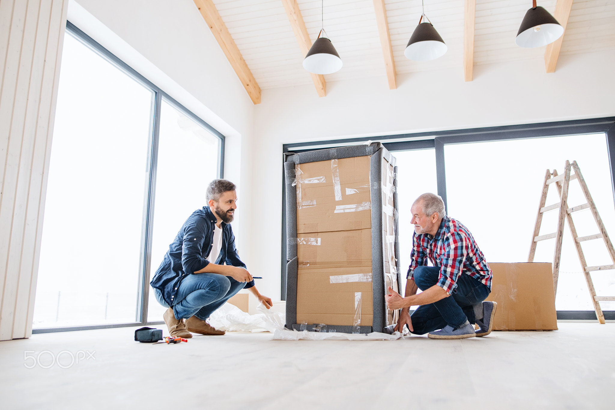 A senior man helping his son with furnishing new house, a new home concept.