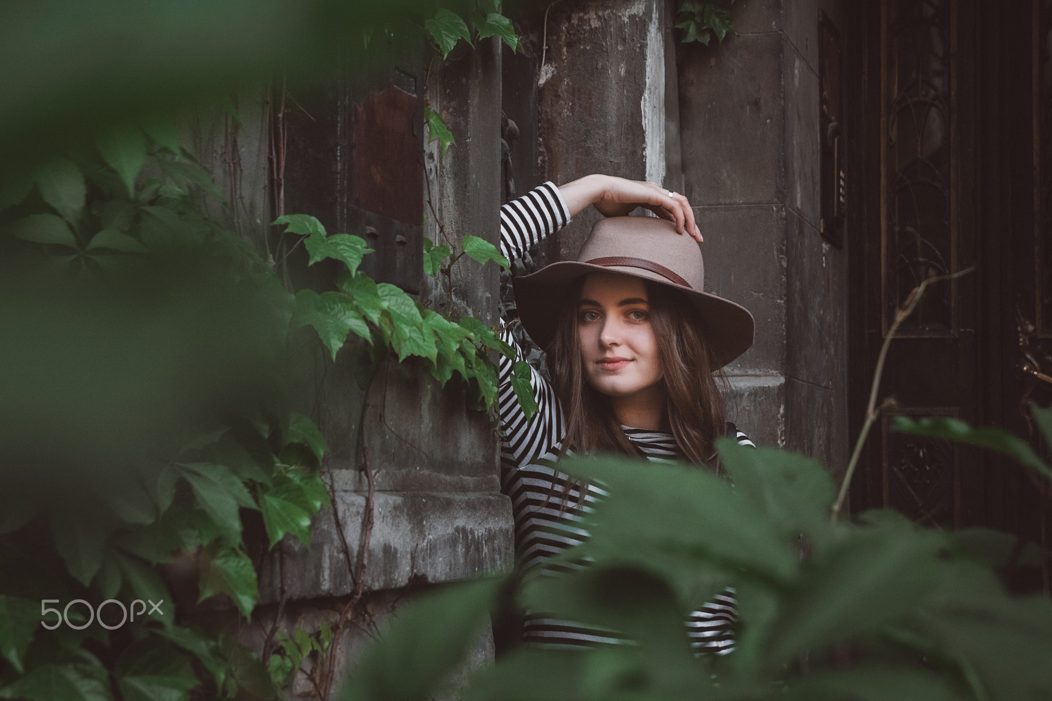 Beautiful woman in a striped shirt holding her hat and looking at a camera.