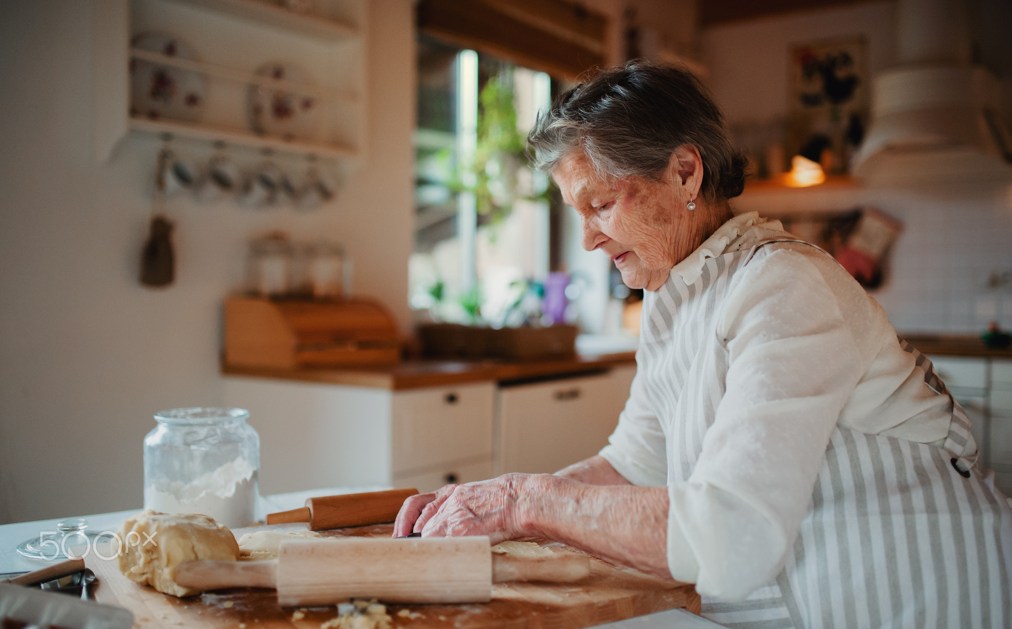 Elderly woman making cakes in a kitchen at home. Copy space.