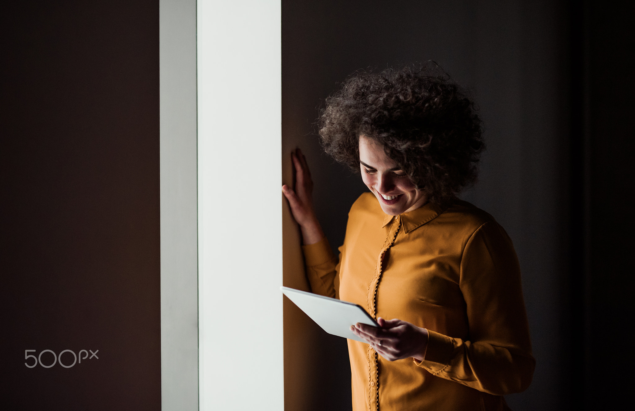 Portrait of a young businesswoman with tablet indoors in an office. Copy space.