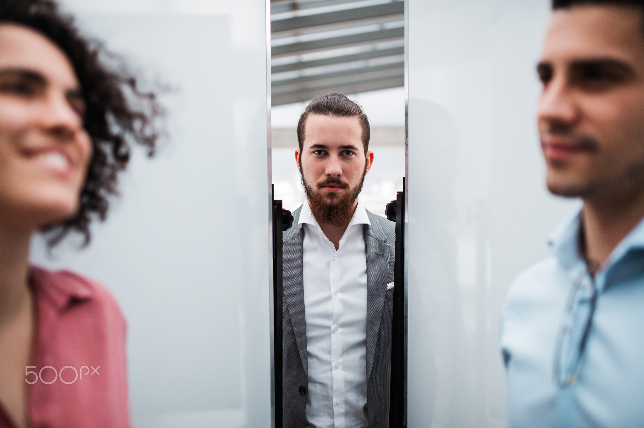 A young businessmanwith colleagues in suit standing in office.