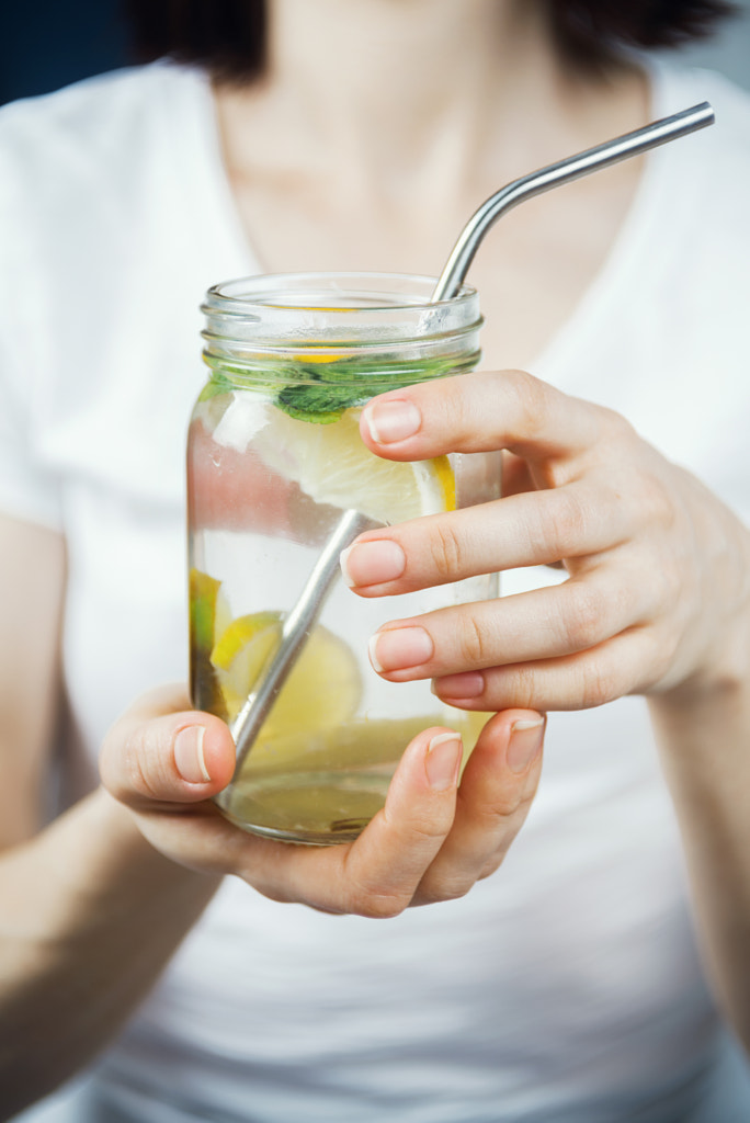 Closeup of woman's hands holding mason jar with sassy lemon and mint water, selective focus by Nataly Lavrenkova on 500px.com